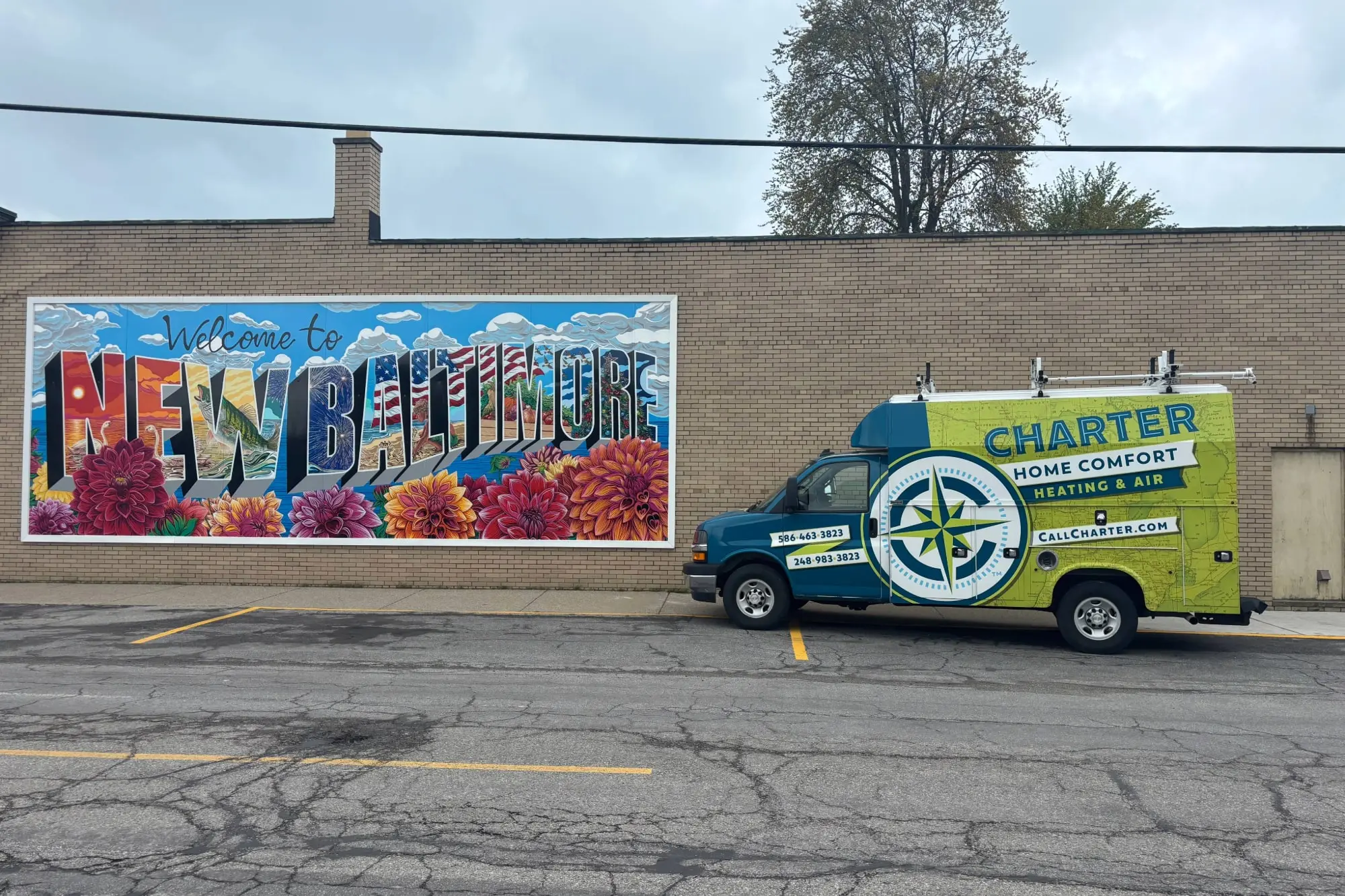 Charter Home Comfort Van Parked by  the Welcome to New Baltimore mural, created by Justin Rose, located at Alfred and Washington streets in New Baltimore, Michigan.  